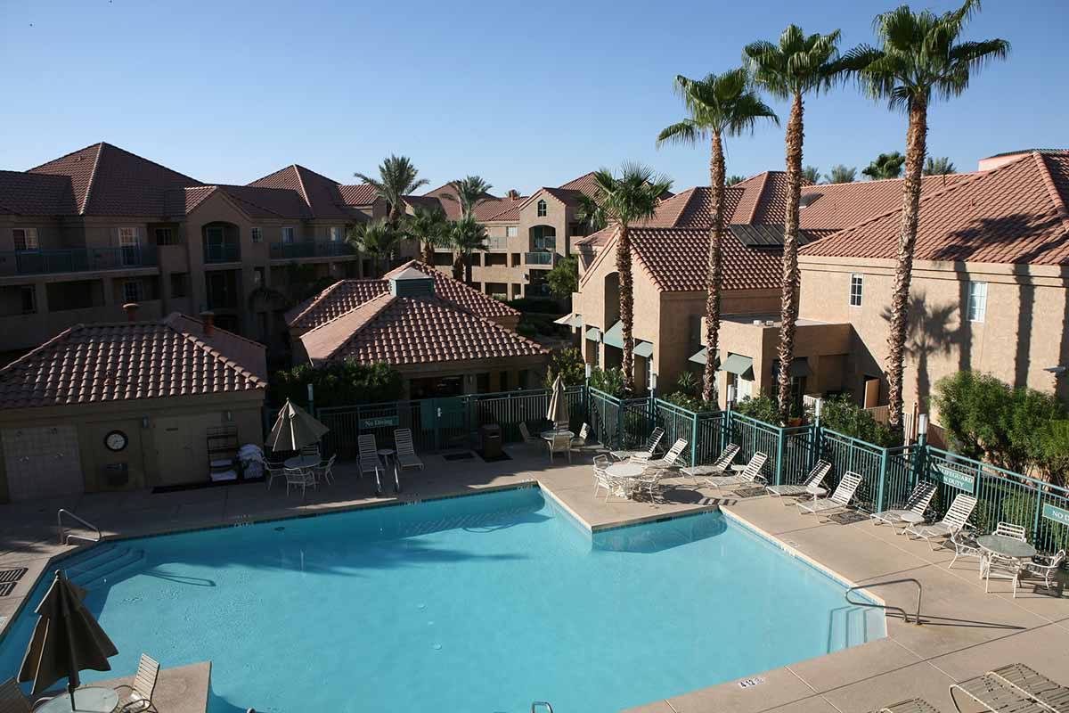 A residential community with a pool, palm trees, and townhomes, typical of properties managed by CAMs or property managers.