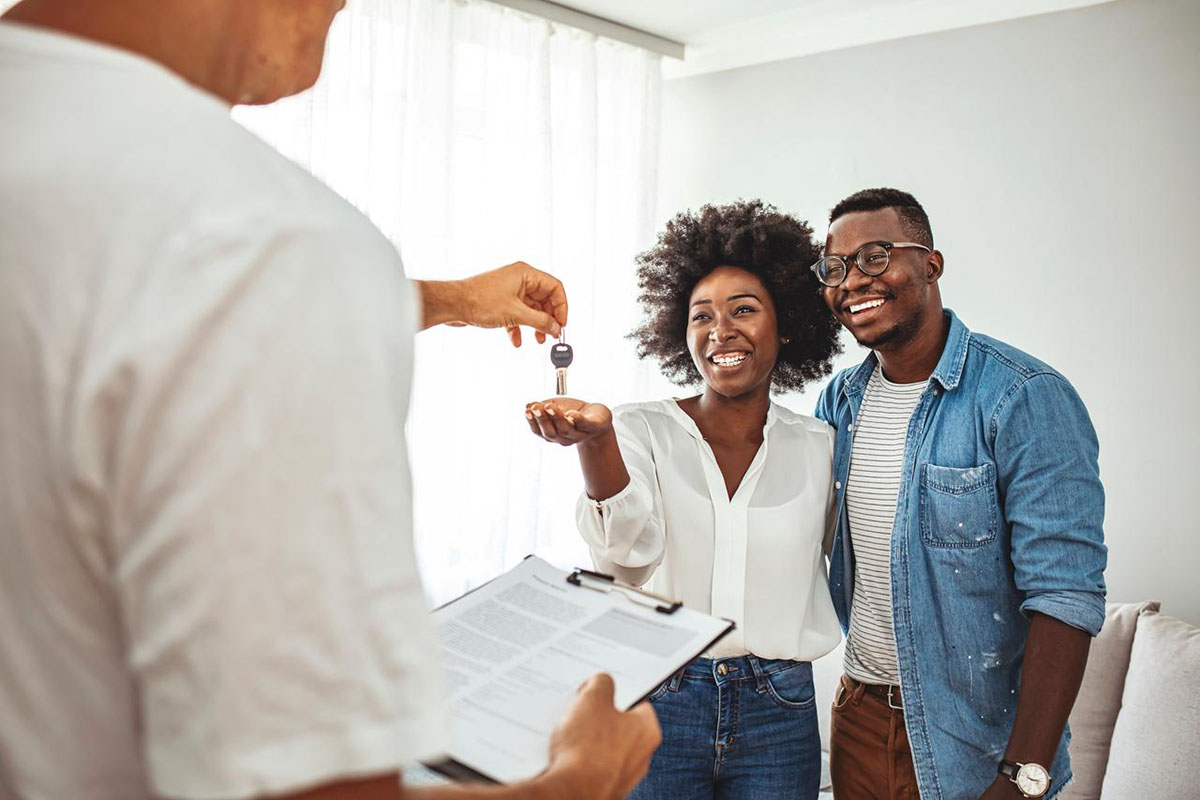 young couple receives keys from a real estate agent – learn how to pay for a real estate license as a veteran