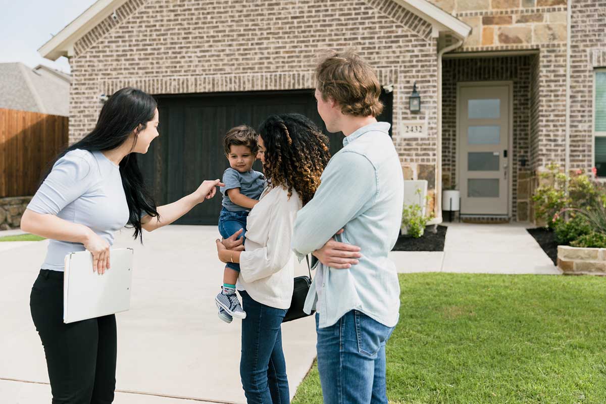 real estate agent greets toddler while showing home to family