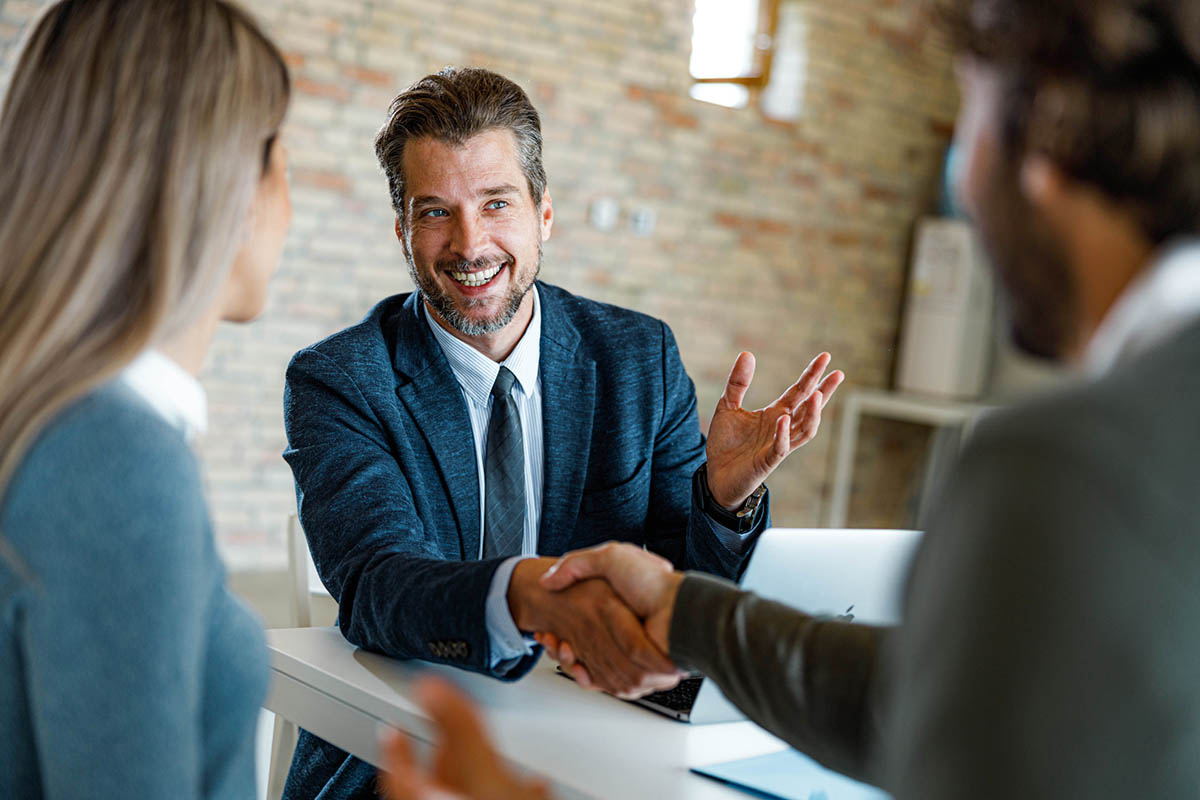 real estate agent in challenging market shakes hands with clients